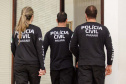Três policiais civis aparecem de costas para a foto