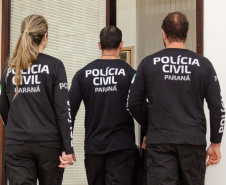 Três policiais civis aparecem de costas para a foto