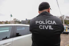 policial civil de costas para a imagem. Ele usa jaqueta e boné