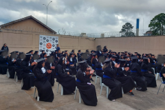 84 formandas do CIS usando becas. Elas estão sentadas em cadeiras