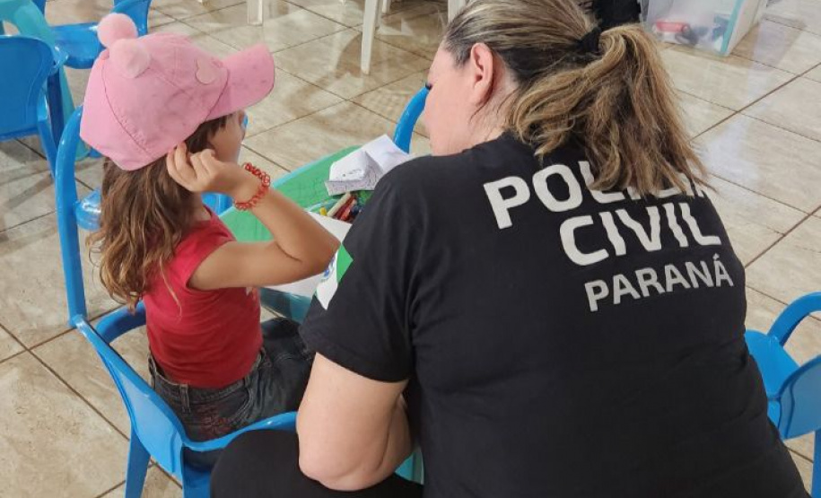 policial civil mulher conversa com criança usando boné rosa
